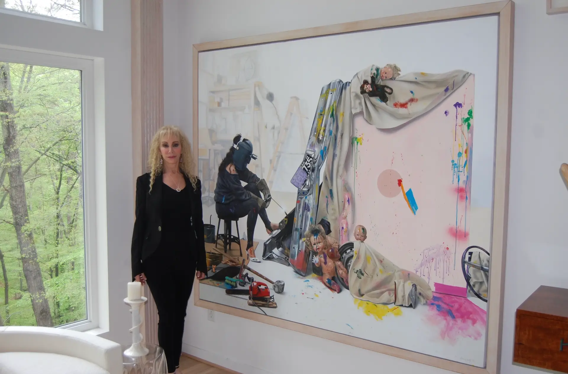 Sherry Wolf standing in front of painting Artist in The Studio